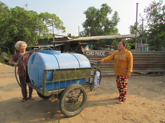 Cụ Huỡn và chị Cẩm đang cho nước cho bà con đến xin